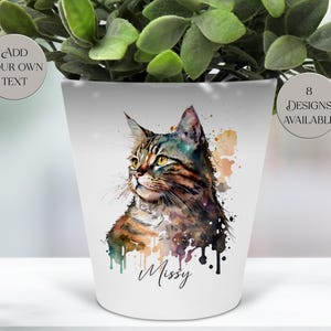 May include: White ceramic plant pot with a watercolour painting of a tabby cat named Missy. The cat has brown, black, and blue markings. The pot has the text "Add Your Own Text" and "8 Designs Available".