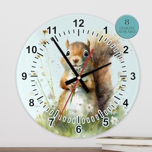 May include: A round wall clock featuring a watercolor illustration of a squirrel holding flowers. The clock has black hands and numerals, with a light blue background. The words "8 Designs Available" are in a teal circle.