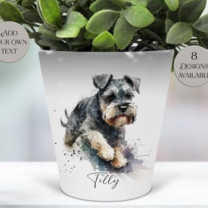 May include: White ceramic plant pot featuring a watercolor-style Schnauzer dog design. The dog is depicted in shades of gray, black, and tan, with the name "Tilly" written below. The pot has the text "Add Your Own Text" and "8 Designs Available".