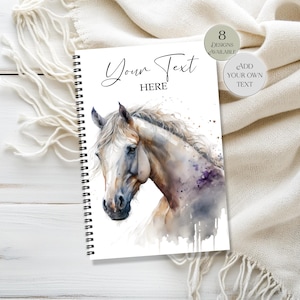 May include: A spiral-bound notebook featuring a watercolour illustration of a horse head on the cover. The text "Your Text HERE" is printed at the top. Two circular badges are visible, one stating "8 DESIGNS AVAILABLE" and "ADD YOUR OWN TEXT".