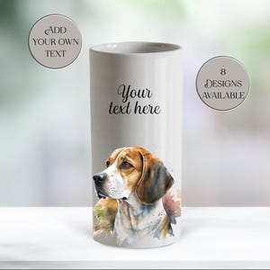 May include: A white ceramic vase with a watercolour painting of a beagle dog. The vase has the text "Your text here" and "Add your own text" and "8 designs available". The dog has brown, white, and black fur.