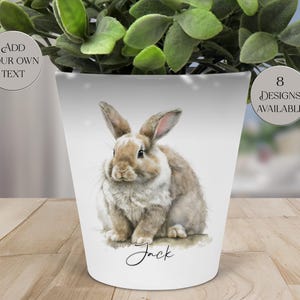 May include: White ceramic planter with a watercolor illustration of a brown and white rabbit. The planter has the name "Jack" written in script. The planter also has the text "Add Your Own Text" and "8 Designs Available".