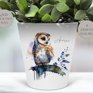 May include: White ceramic plant pot with a watercolour owl design. The owl is perched on a branch with blue and purple leaves. The pot has the name "Aimee" and the text "Add your own text" and "8 designs available".