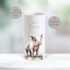 May include: A white cylindrical tumbler featuring a watercolor illustration of a small piglet. The text "Your Text Here" is printed in black script above the piglet. Two circular badges state "ADD YOUR OWN TEXT" and "8 DESIGNS AVAILABLE".