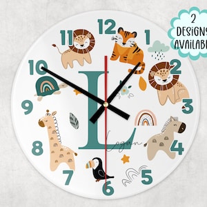 May include: A white round clock with a teal letter L in the centre. The clock face features a variety of animal illustrations, including a lion, tiger, giraffe, zebra, turtle, and toucan. The numbers 1 through 12 are displayed around the clock face.