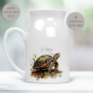 May include: A white ceramic mug featuring a watercolour illustration of a turtle on the front. Above the turtle, the name Poppy is printed in black script. Two circular text overlays state Add Your Own Text and 8 Designs Available.