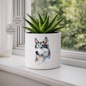 Könnte beinhalten: Weißer Keramik-Pflanztopf mit einem Husky-Hundeporträt im Aquarellstil. Der zylindrische Topf enthält eine grüne Sukkulentenpflanze. Der Text "Your Text" befindet sich unter dem Hundeporträt. Zusätzlicher Text auf der linken Seite lautet "Add Your Own Text" und "8 Designs Available".