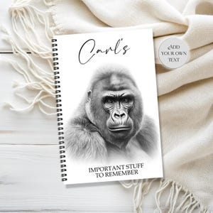 May include: A spiral-bound notebook with a grayscale image of a gorilla on the cover. The cover also features the name "Carl's" in cursive and the text "IMPORTANT STUFF TO REMEMBER". A small circular sticker on the right says "ADD YOUR OWN TEXT".