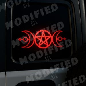 May include: A red vinyl decal featuring a triple moon symbol with a central pentagram and arrows. The decal is applied to a black vehicle window. The word "MODIFIED SIX" is printed in white diagonally across the window.
