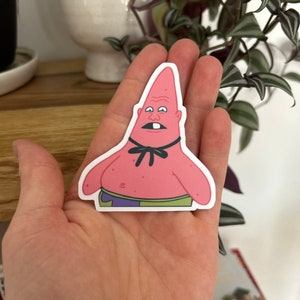 May include: A pink cartoon character with a surprised expression, wearing a black bow tie and purple and green shorts. The character is a sticker.