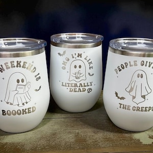 May include: Three white insulated wine tumblers with silver rims and lids. Each tumbler features a ghost graphic and text: "My Weekend Is Boooked", "OMG I'm Like Literally Dead", and "People Give Me The Creeps". Bats are also included in the design.