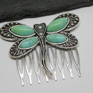 Puede incluir: Un peine para el cabello de metal plateado con forma de libélula. Las alas están adornadas con piedras ovaladas de color turquesa. El peine tiene siete púas plateadas.