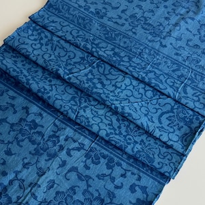 Könnte beinhalten: Ein gefaltetes Stück blauer Stoff mit einem Blumenmuster. Der Stoff hat eine strukturierte Oberfläche und einen leicht verblassten Look.