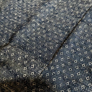 May include: Close-up of a black and white woven fabric with a repeating pattern. The fabric has a textured surface and a slightly rough feel.