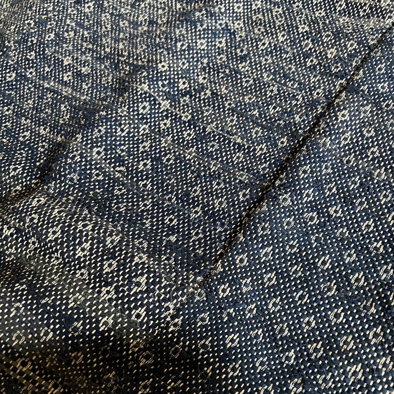 May include: Close-up of a black and white woven fabric with a repeating pattern. The fabric has a textured surface and a slightly rough feel.