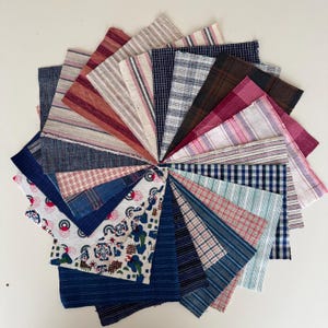 Puede incluir: Una disposición circular de muestras de tela en varios patrones y colores. Las muestras incluyen rayas, cuadros y diseños florales en tonos de azul, rojo, blanco y marrón. Las telas están dispuestas en un patrón radial.