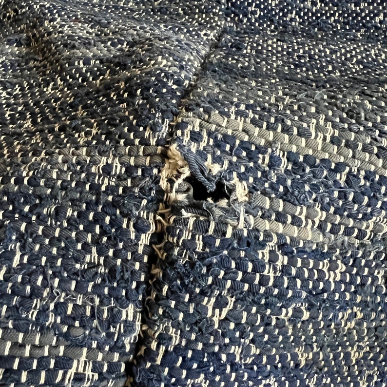 May include: A close-up of a blue and white woven rug with a hole in the centre. The rug is made of a thick, textured material.