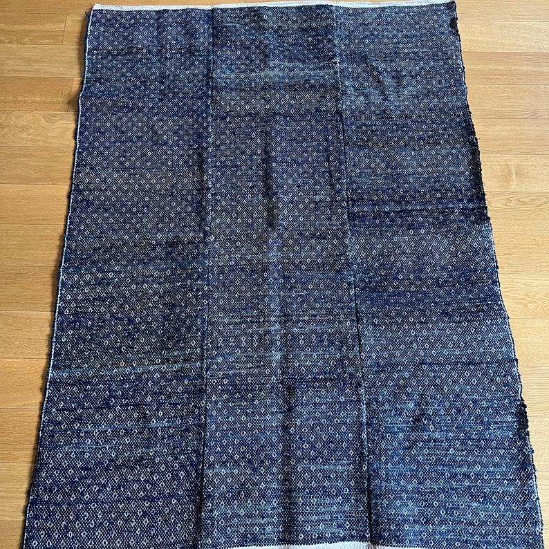 May include: A blue and white patterned rug with a woven texture. The rug is made of a soft, durable material and is perfect for adding a touch of style to any room.