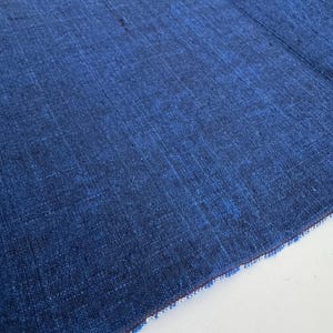 Könnte beinhalten: Ein tiefblauer Textilstoff mit einer sichtbaren Webstruktur und Variationen in der Farbintensität. Das Material zeigt ein dichtes, ineinandergreifendes Muster aus dunkel- und mittelblauen Fäden, das ein gleichmäßiges Oberflächenbild erzeugt.