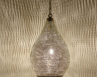 May include: A teardrop-shaped pendant light fixture with a perforated metal shade. The shade is a dark bronze color and is covered in small, evenly spaced holes. The light is suspended from a chain and illuminates the surrounding area.