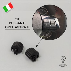 May include: Two black plastic replacement buttons for an Opel Astra H steering wheel. The buttons are ribbed and have a clip on the back. The image also shows a close-up of the steering wheel with the buttons in place.