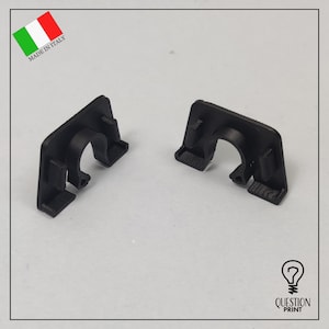 Könnte beinhalten: Zwei schwarze Kunststoffclips mit einer gebogenen Öffnung. Die Clips sind so konzipiert, dass sie Kabel oder Drähte an Ort und Stelle halten.