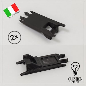 Puede incluir: Dos piezas de plástico negro impresas en 3D con forma rectangular y una pequeña abertura en el centro. Las piezas están diseñadas para ser utilizadas como soporte para un objeto impreso en 3D. La imagen incluye el texto "MADE IN ITALY" y "2x".