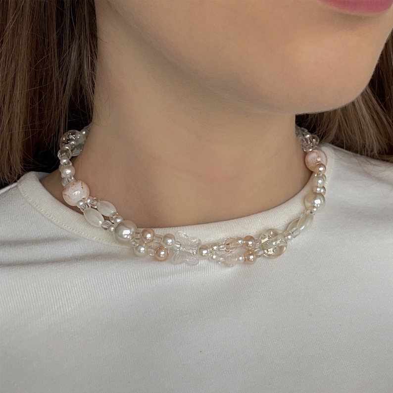Peut inclure: Un collier d&eacute;licat &agrave; deux rangs avec des perles blanches et roses. Le collier pr&eacute;sente un m&eacute;lange de perles rondes et ovales, cr&eacute;ant un look unique et &eacute;l&eacute;gant.