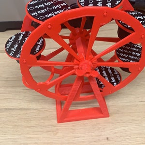 Könnte beinhalten: Ein rotes, 3D-gedrucktes Riesenrad mit schwarzen Kaffeekapseln, auf denen "extra forte" steht.