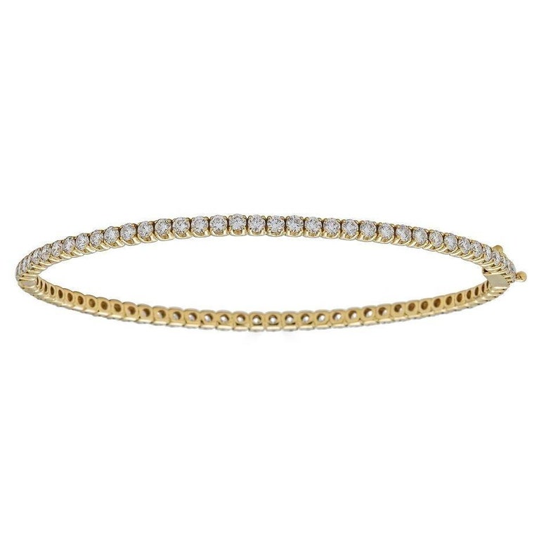 May include: A gold tennis bracelet with a row of round diamonds.