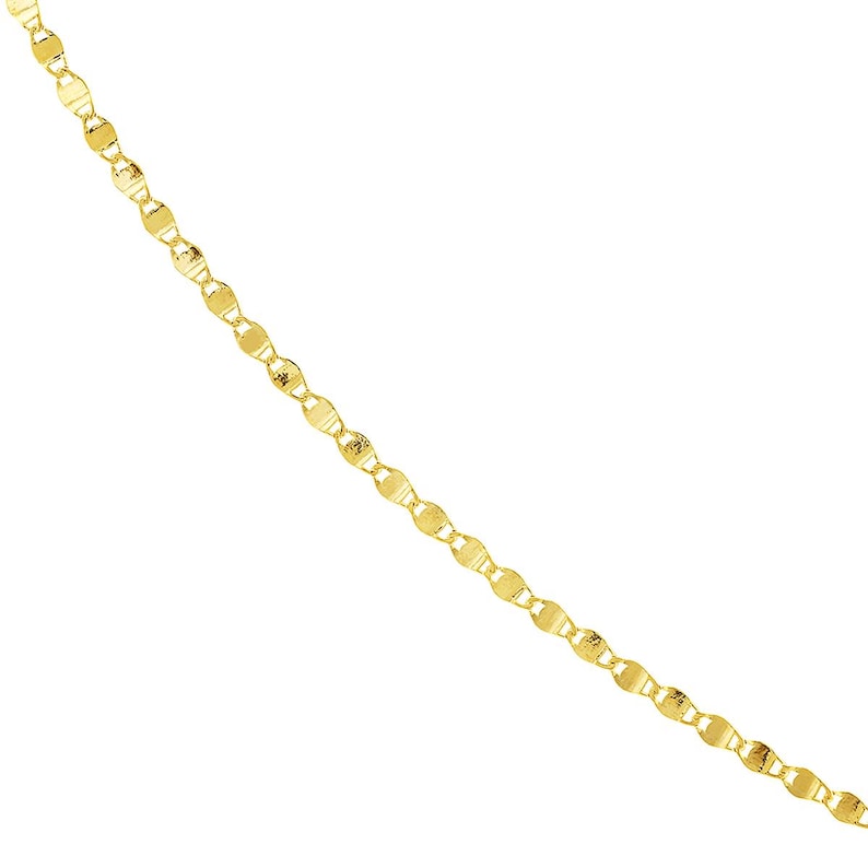 May include: A delicate gold necklace with a repeating pattern of small, flat, circular links. The chain is angled across a white background, showcasing the jewelry's shine and design. The necklace appears to be made of solid gold.