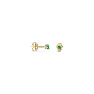 May include: A pair of gold stud earrings with small green gemstones.