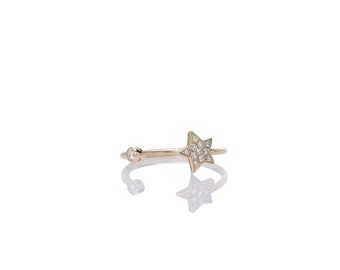 May include: A gold ring with a small star-shaped design set with clear stones. The ring is open and has a small round stone on the other side of the star.
