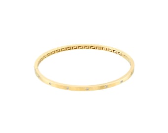 Puede incluir: Un brazalete de oro con un diseño de llave griega y pequeñas piedras transparentes.