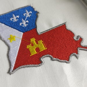 Pode incluir: Um remendo bordado do estado da Louisiana. O remendo &eacute; vermelho, branco e azul com uma estrela amarela e um castelo amarelo no centro. O contorno do estado &eacute; cinza.