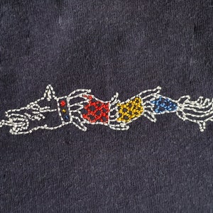 May include: White embroidered design of a dragon with red, yellow, and blue accents on a dark blue fabric.
