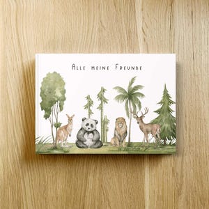 Könnte beinhalten: Ein Hardcover-Buch mit dem deutschen Text "Alle Meine Freunde" und Illustrationen eines Kängurus, Pandas, Löwen und Hirsches in einer Waldlandschaft. Das Cover zeigt grüne Bäume und Gras.