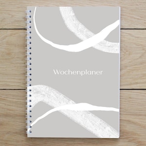 May include: A gray spiral bound notebook with white abstract brushstrokes and the text "Wochenplaner" on the cover.