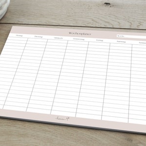 May include: A blank weekly planner with a light brown background and the word "Wochenplaner" at the top. The planner has columns for each day of the week, Monday through Sunday, with the days labelled in German.