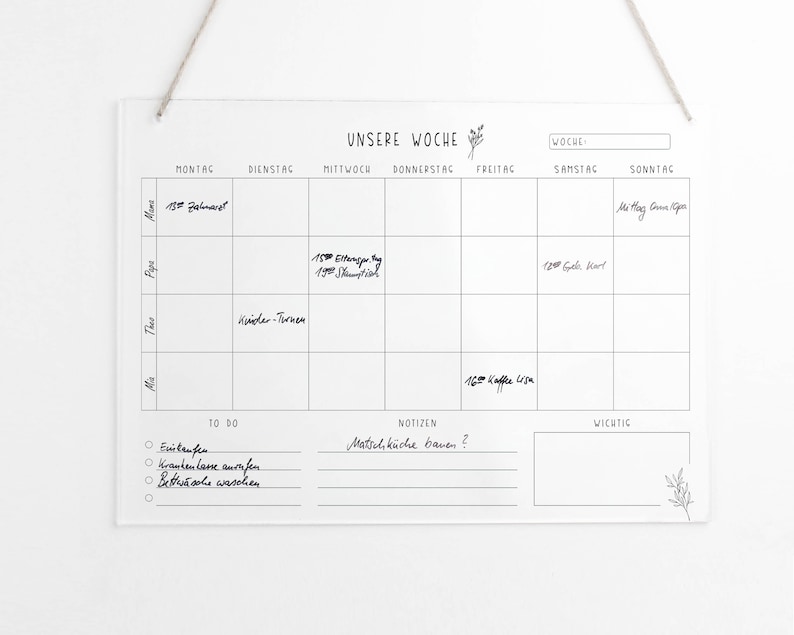 May include: A white dry-erase weekly planner with a black grid and the words "Unsere Woche" (Our Week) at the top. The planner has columns for each day of the week, with space for writing appointments and notes. There is a "To Do" list, a "Notes" section, and a "Important" section.