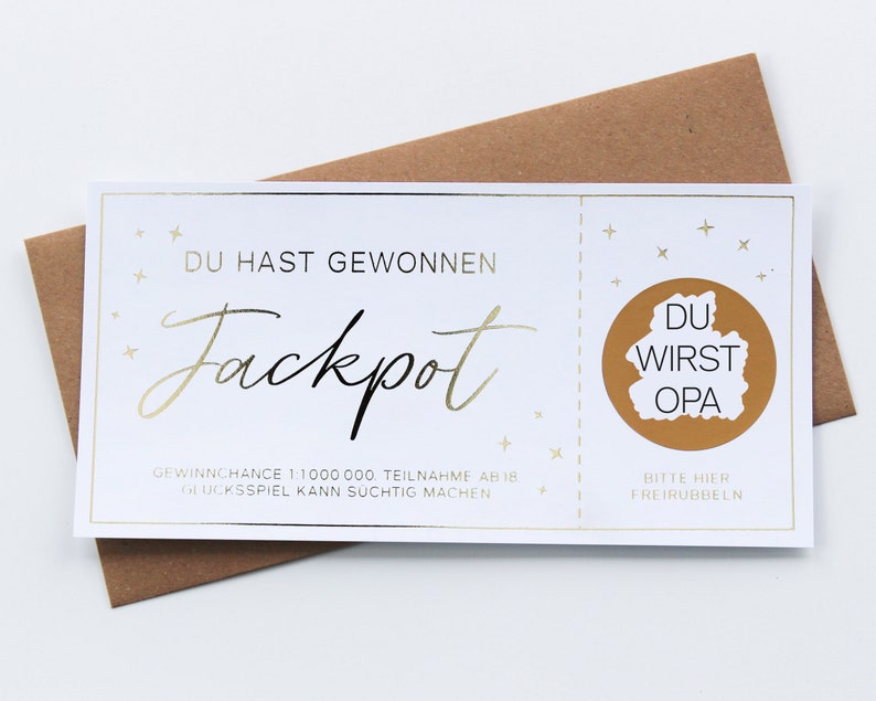 May include: A white rectangular scratch-off lottery ticket with gold foil accents. The text reads DU HAST GEWONNEN Jackpot, GEWINNCHANCE 1:1000000, TEILNAHME AB 18, GLUCKSSPIEL KANN SUCHTIG MACHEN, and BITTE HIER FREIRUBBELN with DU WIRST OPA inside.