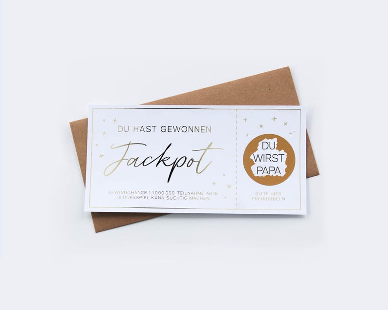 May include: A white rectangular lottery ticket with gold foil accents and the German text DU HAST GEWONNEN Jackpot, featuring a circular gold scratch-off area with the hidden text DU WIRST PAPA, placed on top of a brown paper envelope.