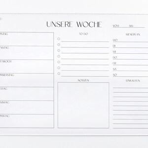 以下が含まれることがあります： ドイツ語で「Unsere Woche」（私たちの週）と書かれた白いアクリル製の週間プランナー。プランナーは週の各日に分けられており、やることリスト、食事プラン、メモ、買い物リストのためのスペースがあります。