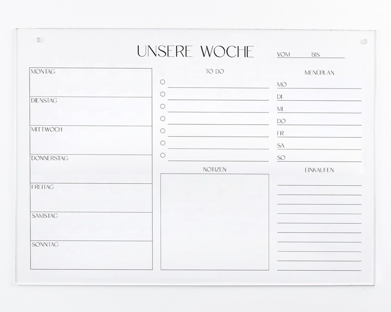 以下が含まれることがあります： ドイツ語で「Unsere Woche」（私たちの週）と書かれた白いアクリル製の週間プランナー。プランナーは週の各日に分けられており、やることリスト、食事プラン、メモ、買い物リストのためのスペースがあります。