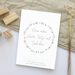 May include: A white book with a gray floral wreath design and the text "Deine ersten Worte, Sätze und Geschichten" and "Ein Wortschatzsammler von deinem kleinen Findelkind".