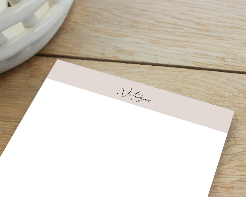 Puede incluir: Un bloc de notas blanco con un encabezado beige que dice "Notizen" en cursiva negra.