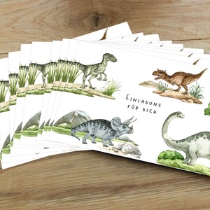 Pode incluir: Um conjunto de cart&otilde;es brancos com ilustra&ccedil;&otilde;es de dinossauros e o texto "Einladung f&uuml;r dich" (Convite para voc&ecirc;). Os dinossauros s&atilde;o um velociraptor verde, um tiranossauro rex marrom, um triceratops cinza e um braquiossauro cinza.