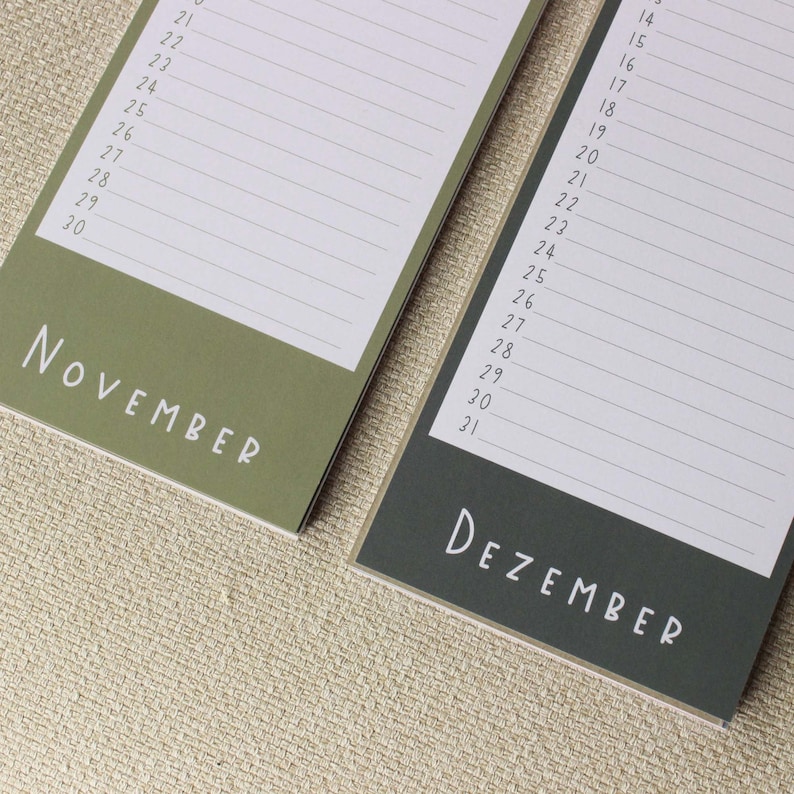 May include: A close-up of a calendar with the months November and December. The calendar is printed on green and gray paper with white text.