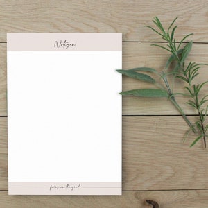 Peut inclure: Un bloc-notes blanc avec un en-tête et un pied de page roses. L'en-tête indique "Notizen" et le pied de page indique "focus on the good".