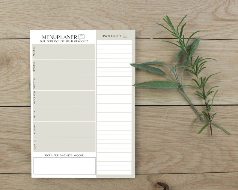 May include: A white printable meal planner with the text "MEN&Uuml;PLANER GUT GEPLANE IST HALB GEKOCHT!" and a grocery list section. The planner has a section for each day of the week and a section for ideas for the next week.